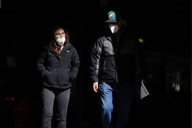 AP Photo | Matt Rourke
In this Wednesday, March 3, 2021 file photo, people wearing face masks as a precaution against the coronavirus walk through a shaft of light on a street in Philadelphia. On Tuesday, April 27, 2021, U.S. health officials say fully vaccinated Americans dont need to wear masks outdoors anymore unless they are in a big crowd of strangers, and those who are unvaccinated can go without a face covering outside in some cases, too.